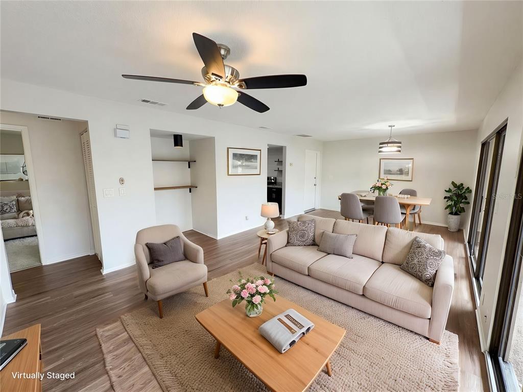 A living room with wood-look flooring, a beige sofa, an armchair, and a dining area — 240 MOREE LOOP UNIT 3, WINTER SPRINGS, FL