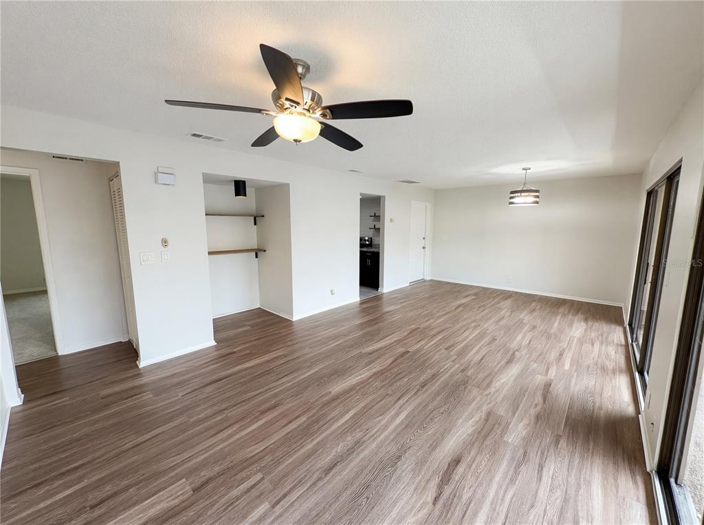 An open-concept living area features wood-look flooring, a ceiling fan, and built-in wall shelving — 240 MOREE LOOP UNIT 3, WINTER SPRINGS, FL