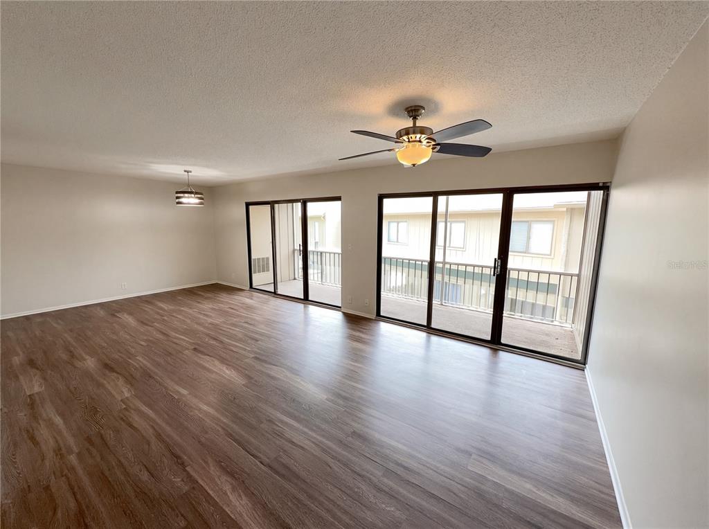 An empty living room features wood-look flooring, a ceiling fan, and sliding glass balcony doors — 240 MOREE LOOP UNIT 3, WINTER SPRINGS, FL