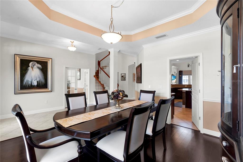 A dining room with dark wood floors and a hutch sits beside a tiled entryway — 5727 SEA TROUT PLACE, APOLLO BEACH, FL