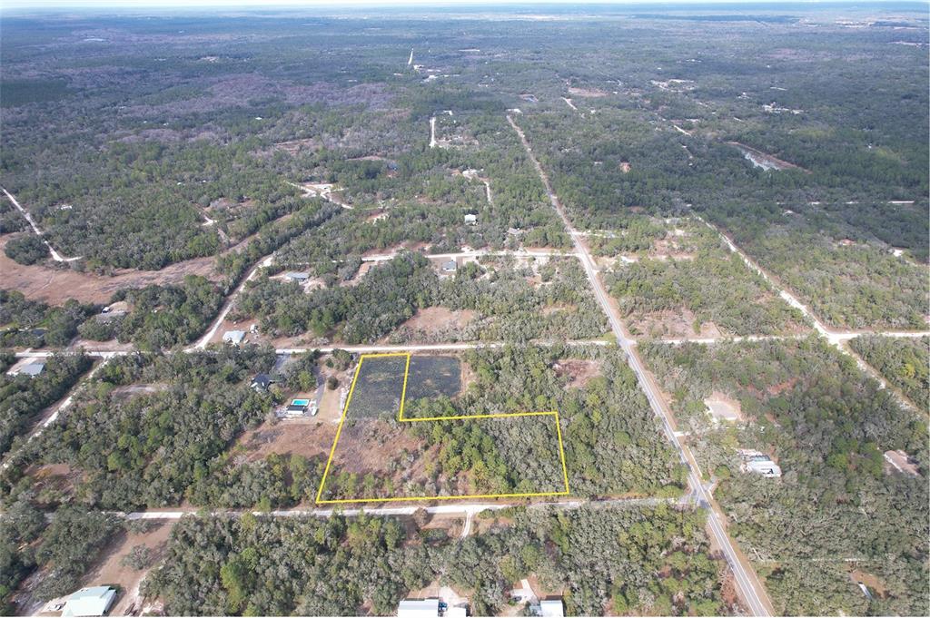 An aerial view shows a vacant, L-shaped plot of land outlined in yellow — BERRYHILL DRIVE, WEBSTER, FL