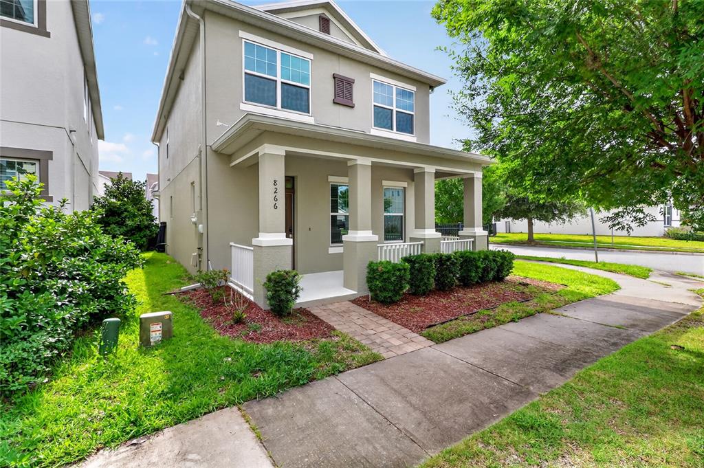 A two-story house with a covered front porch, tan siding, and a small landscaped yard — 8266 BRYCE CANYON AVENUE, WINDERMERE, FL