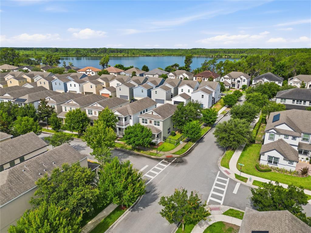 An aerial view shows a suburban neighborhood with houses, streets, and a lake in the background — 8266 BRYCE CANYON AVENUE, WINDERMERE, FL