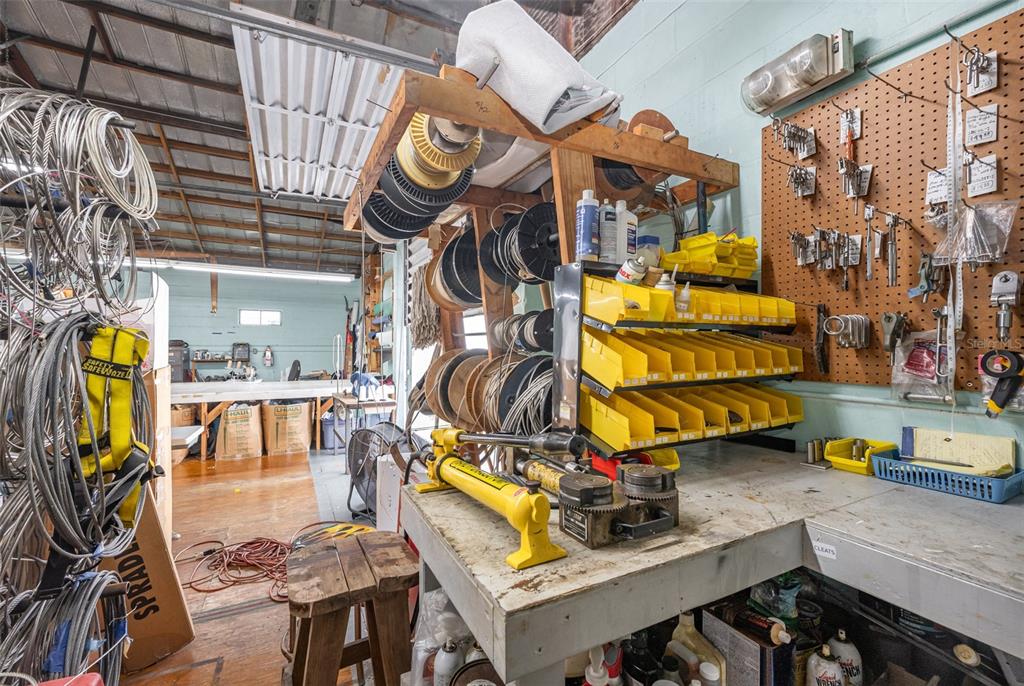 A cluttered workshop features a wooden workbench, a pegboard wall, and various spools of wire — 229 FORREST AVENUE, COCOA, FL