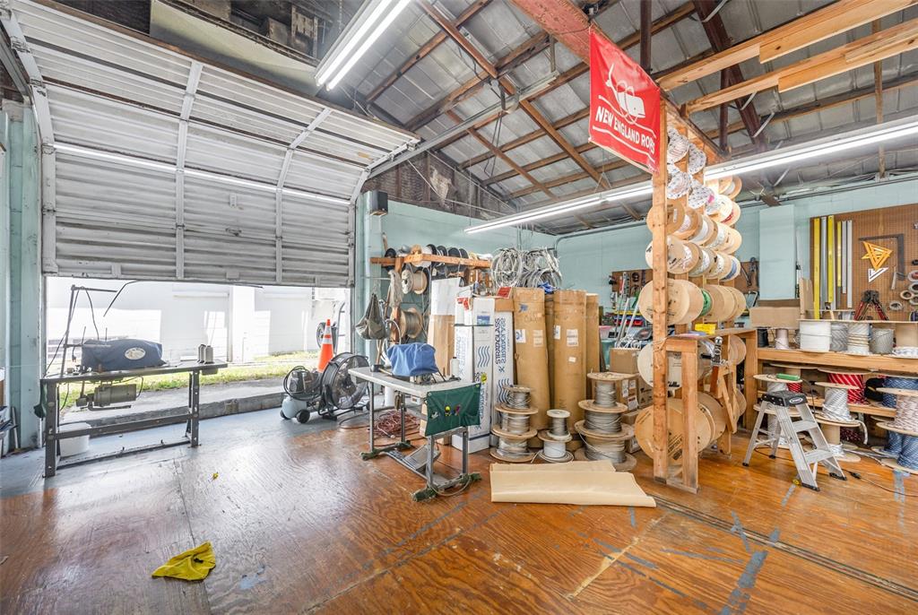 A workshop space features a roll-up garage door, wooden floors, and various spools of rope — 229 FORREST AVENUE, COCOA, FL