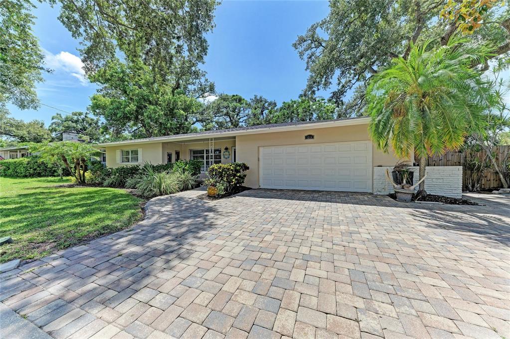 A single-story house with a paved driveway, a white garage door, and mature trees — 1214 21ST STREET W, BRADENTON, FL