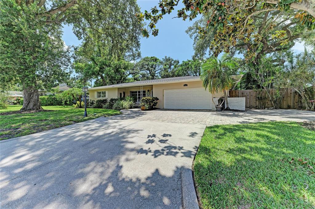 A single-story house with a paved driveway, a two-car garage, and mature trees — 1214 21ST STREET W, BRADENTON, FL