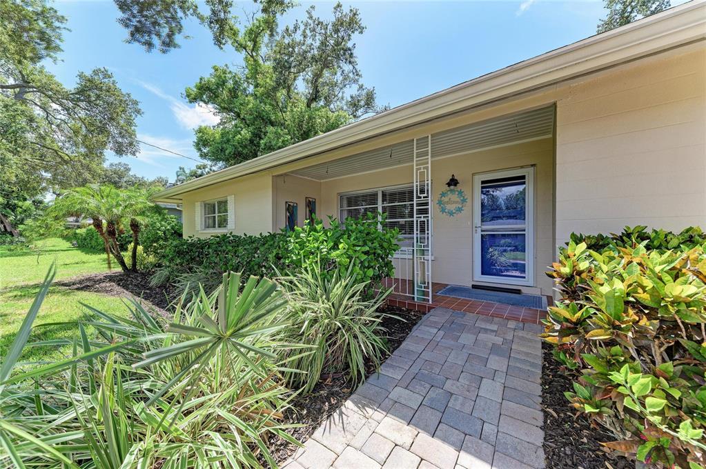 A paved walkway leads to the front entrance of a single-story house with landscaping — 1214 21ST STREET W, BRADENTON, FL