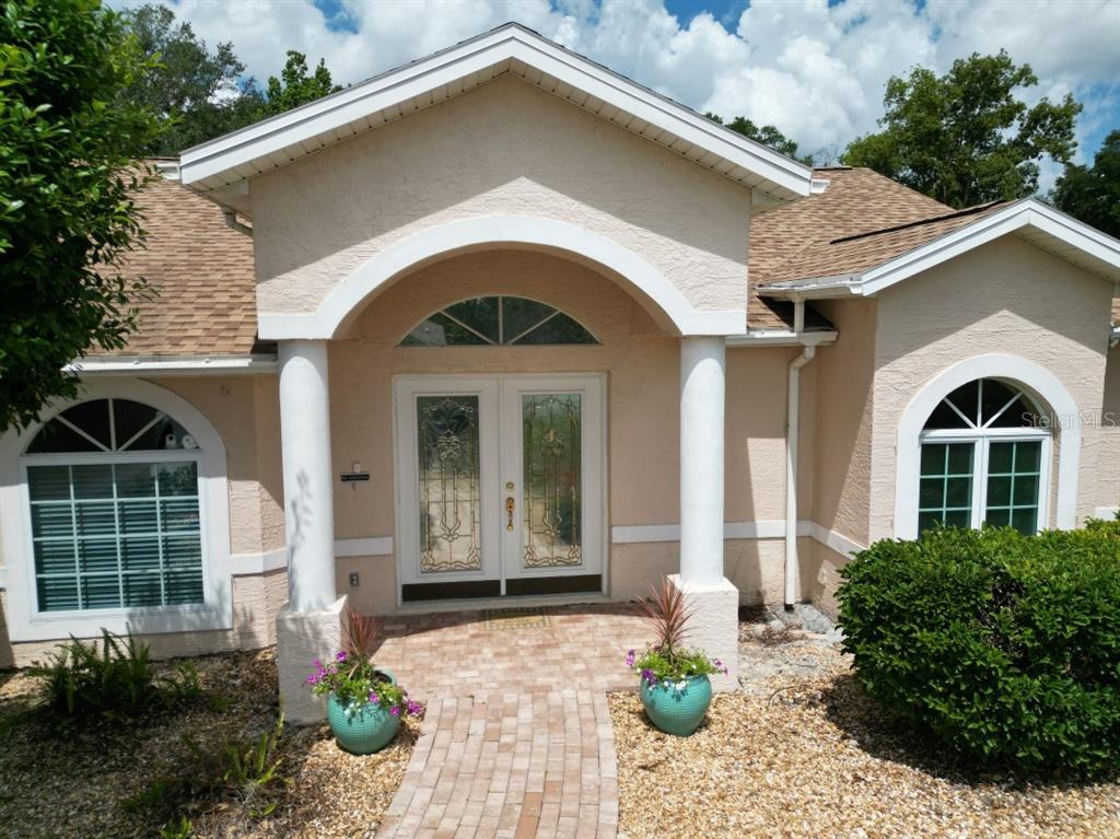 The exterior of a house features a brick walkway leading to a double-door entryway — 12125 KNOTTY PINE LOOP, SAN ANTONIO, FL