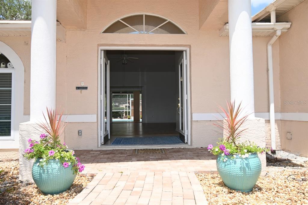 A front entryway features double doors, two large planters, and white columns on a paved porch — 12125 KNOTTY PINE LOOP, SAN ANTONIO, FL