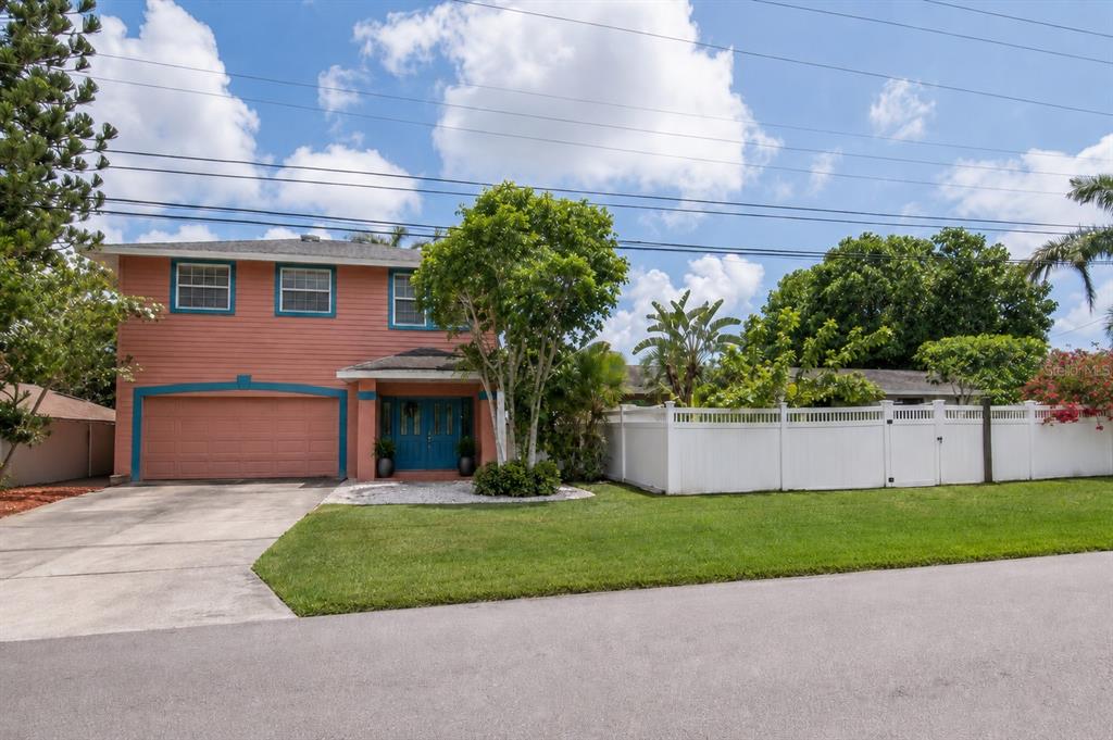 A pink house exterior features a bright blue double front door and a covered porch — 10532 67TH AVENUE, SEMINOLE, FL