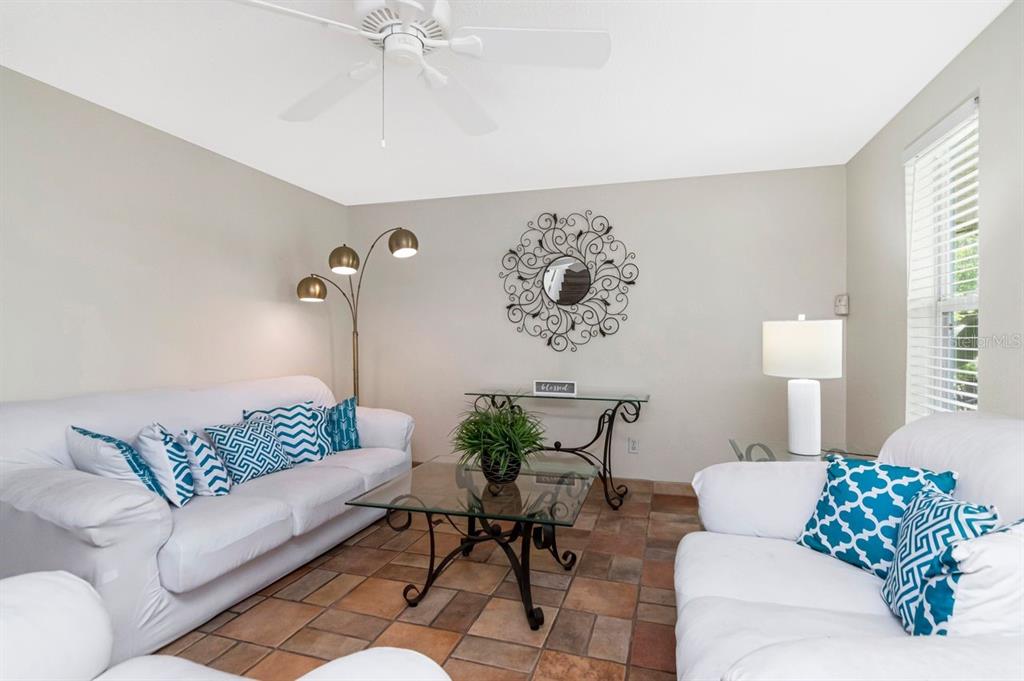 A dining area with a glass table and blue chairs opens into a living room — 10532 67TH AVENUE, SEMINOLE, FL
