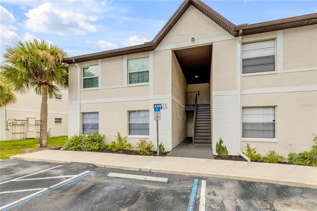 A two-story apartment building exterior features a concrete staircase, a palm tree, and parking spaces — 430 BANANA CAY DRIVE UNIT A, SOUTH DAYTONA, FL
