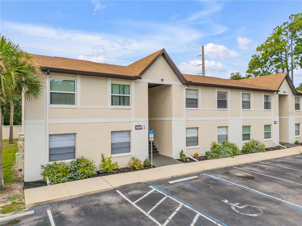 A two-story apartment building with beige stucco walls, a brown shingled roof, and parking spaces — 430 BANANA CAY DRIVE UNIT A, SOUTH DAYTONA, FL