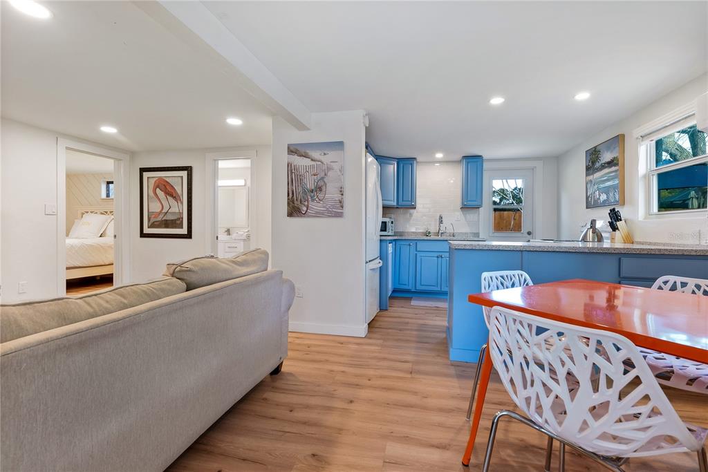 An open-concept living area features a gray sofa, blue kitchen cabinets, and a dining table — 2311 WALDEMERE STREET UNIT B, SARASOTA, FL