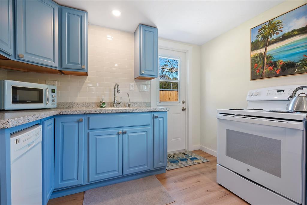A kitchen features blue cabinets, white appliances, a granite countertop, and a white subway tile backsplash — 2311 WALDEMERE STREET UNIT B, SARASOTA, FL