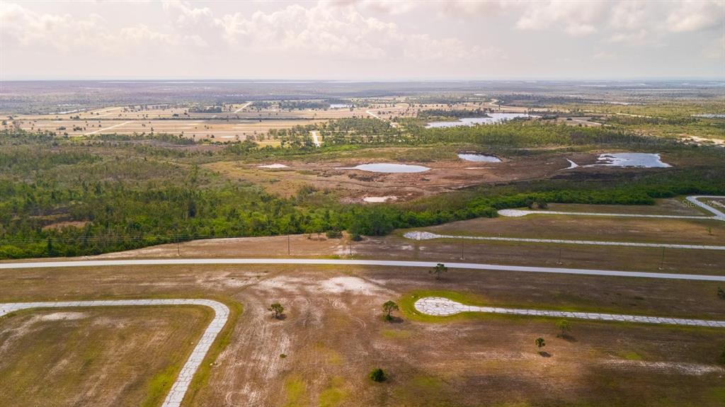 An aerial view shows a large, undeveloped plot of land with paved roads and ponds — 14163 PERMIT COURT, PLACIDA, FL