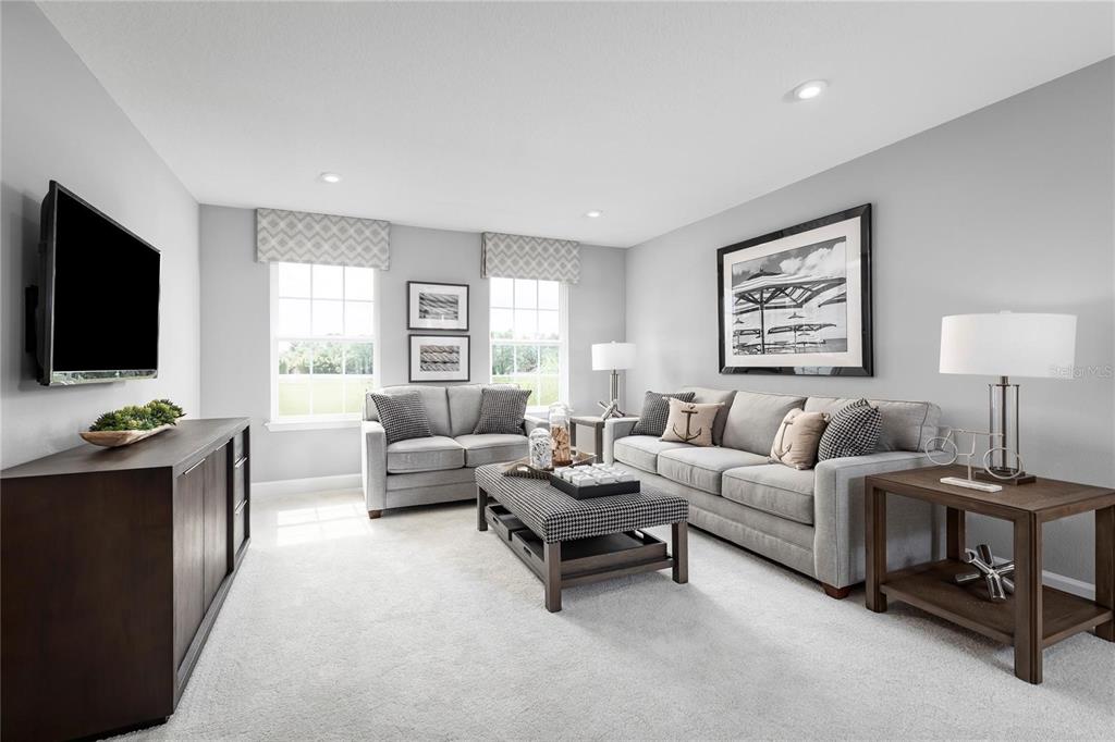 A living room features gray walls, a gray sofa and loveseat, and a dark wood console — 443 HAMMOCK OAKS BOULEVARD, LADY LAKE, FL