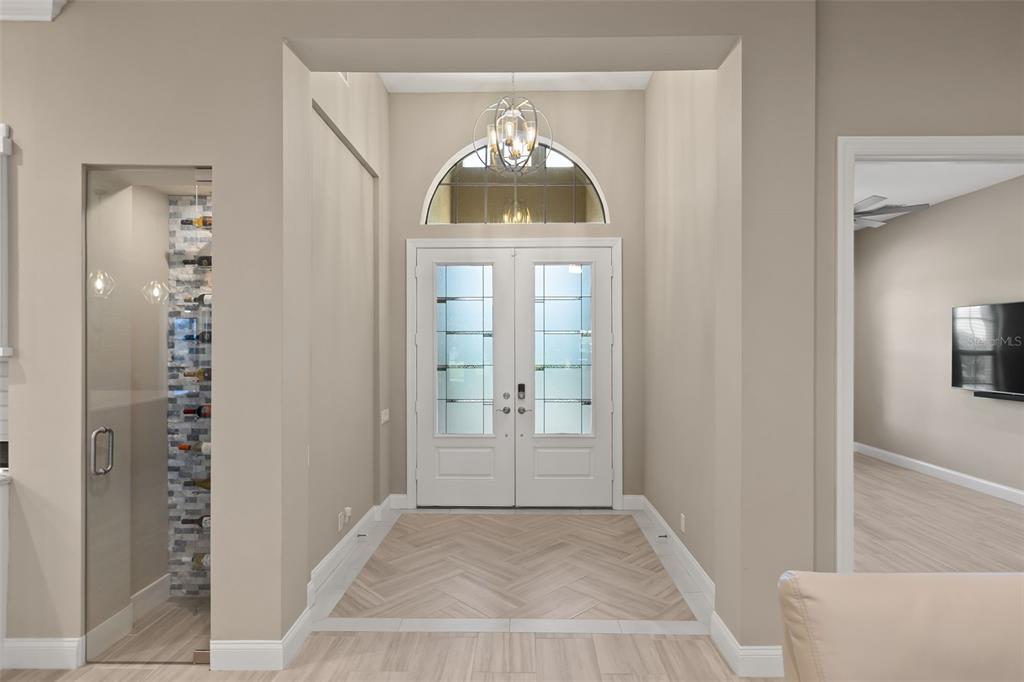 An entryway features double front doors, a glass-enclosed wine display, and herringbone-patterned tile flooring — 209 PINE LILLY COURT, LAKE ALFRED, FL