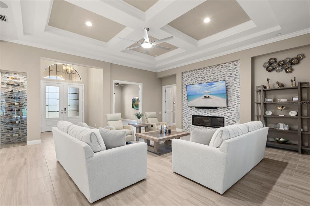 A living room features a coffered ceiling, a tiled fireplace wall, and a built-in wine rack — 209 PINE LILLY COURT, LAKE ALFRED, FL