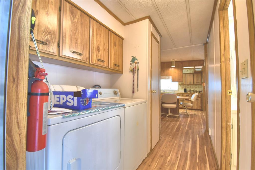 A laundry room with wood cabinets and a white washer leads into a dining area — 2055 S FLORAL AVENUE UNIT 119, BARTOW, FL