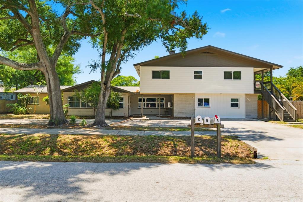 A two-story multi-family house with white siding, stone accents, and three mailboxes in the front — 5136 68TH STREET N, ST PETERSBURG, FL