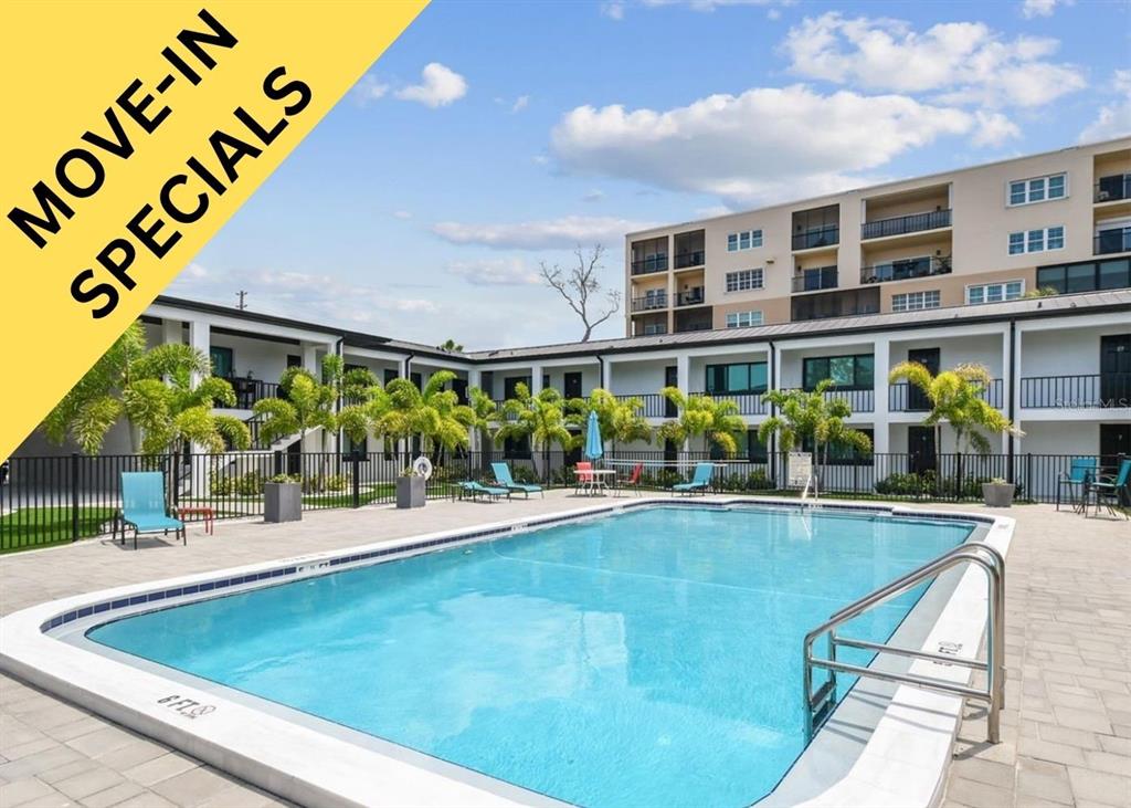 A swimming pool sits in the courtyard of a multi-story apartment building with palm trees — 2942 W BAY DRIVE UNIT 24, BELLEAIR BLUFFS, FL