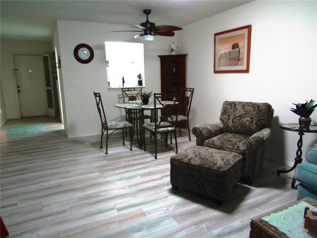 A dining area and living space feature light wood-look flooring and a ceiling fan — 7050 W COUNTRY CLUB DRIVE N UNIT 10-A, SARASOTA, FL