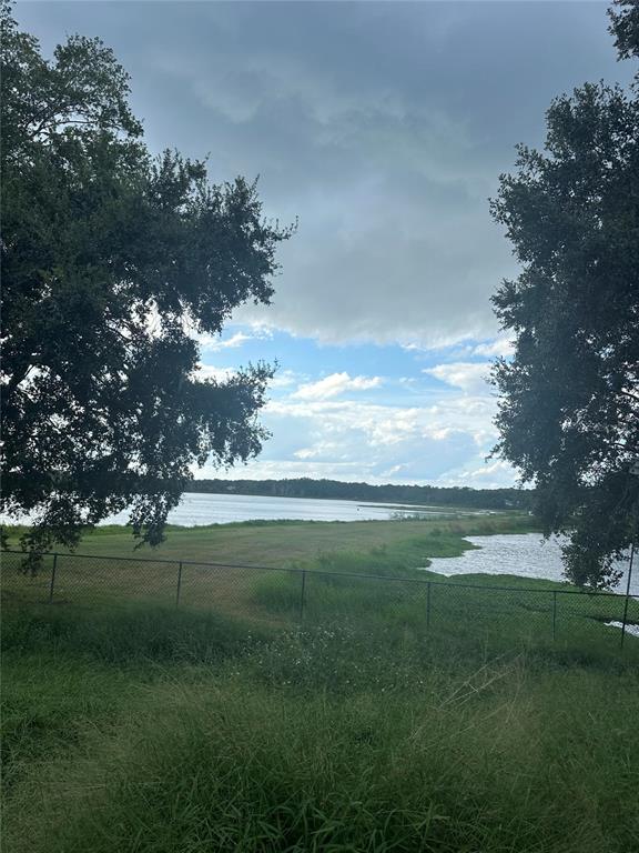 A grassy yard leads to a lake view framed by two large trees behind a fence — 1512 ISON LANE, OCOEE, FL