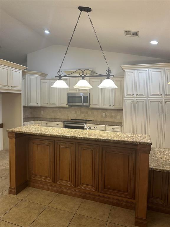 A kitchen features a two-tone island, white upper cabinets, granite countertops, and a pendant light — 1512 ISON LANE, OCOEE, FL