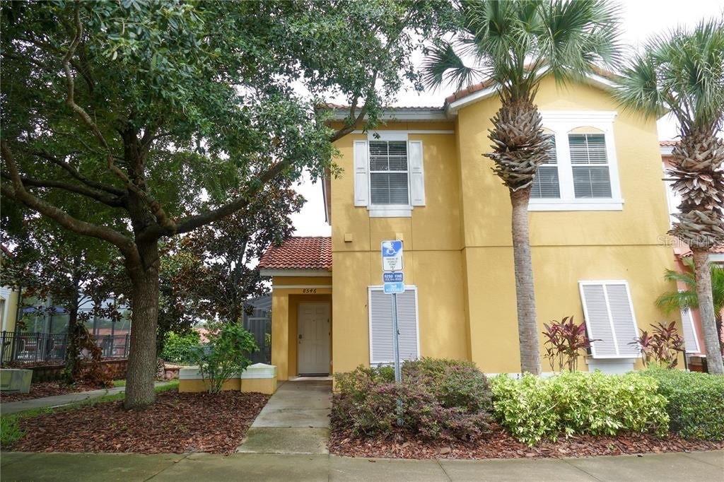 A two-story yellow stucco house with a tiled roof and a palm tree in front — 8546 BAY LILLY LOOP, KISSIMMEE, FL