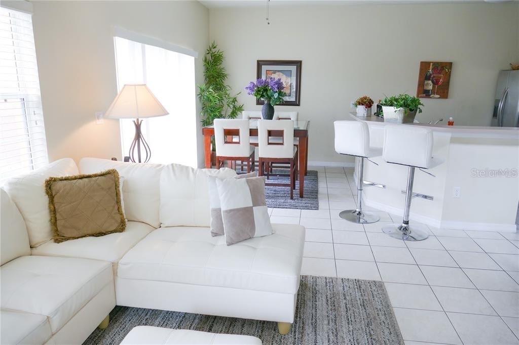 A living room with a white sectional sofa, dining area, and kitchen breakfast bar — 8546 BAY LILLY LOOP, KISSIMMEE, FL