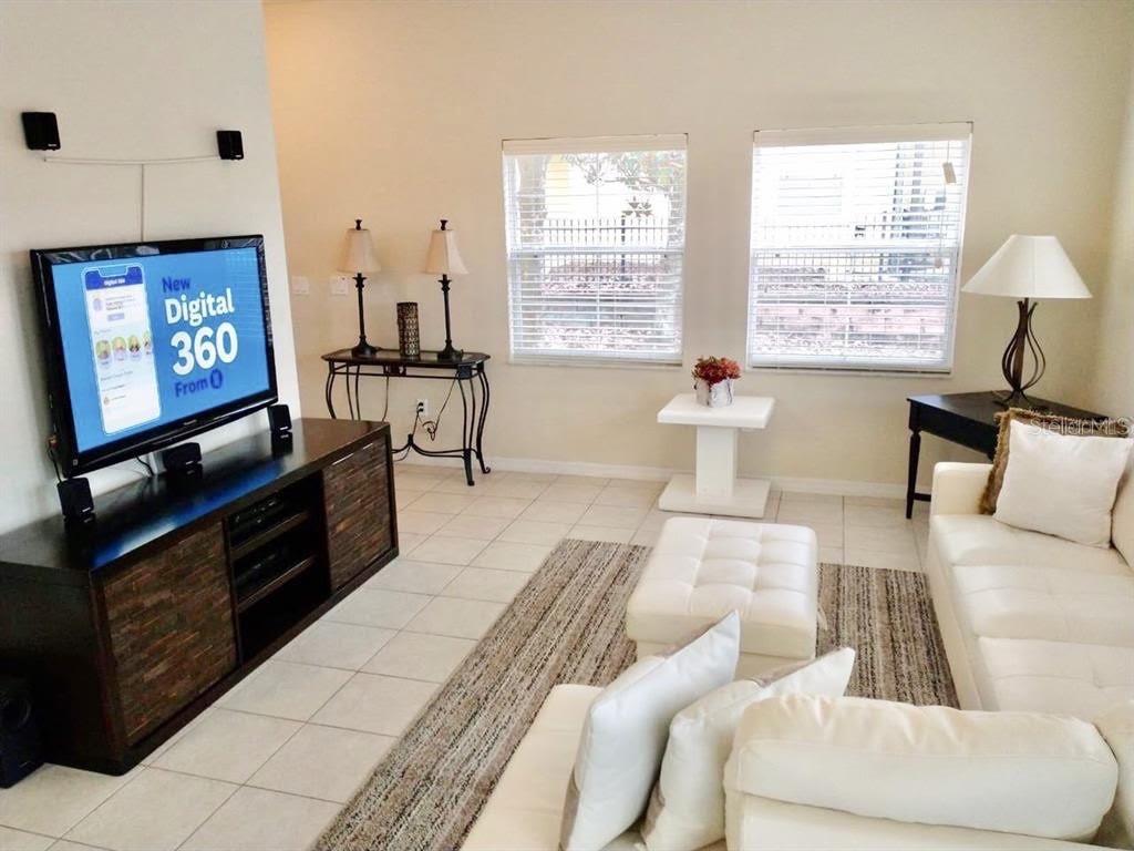 A living room features tile flooring, a white sectional sofa, and a television console — 8546 BAY LILLY LOOP, KISSIMMEE, FL