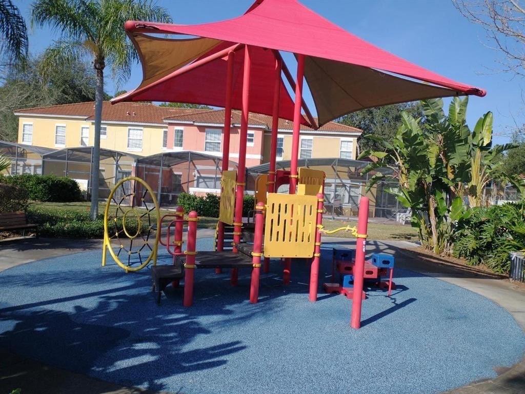 A playground with a red shade canopy and climbing equipment sits on a blue surface — 8546 BAY LILLY LOOP, KISSIMMEE, FL