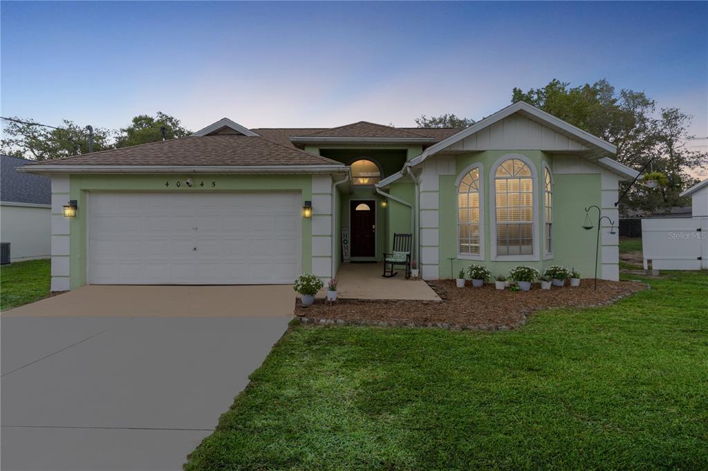 A light green single-story house with a two-car garage and a front porch — 40045 PALM STREET, LADY LAKE, FL