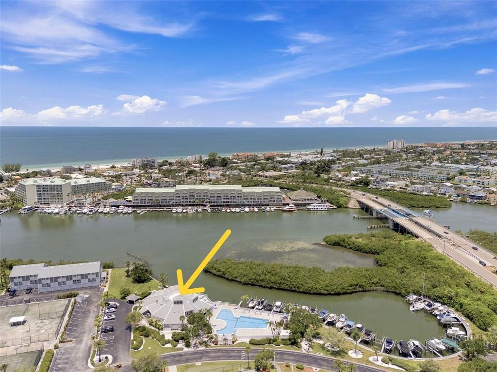 An aerial view shows a circular building with a pool and boat slips nearby — 14800 WALSINGHAM ROAD UNIT 702, LARGO, FL
