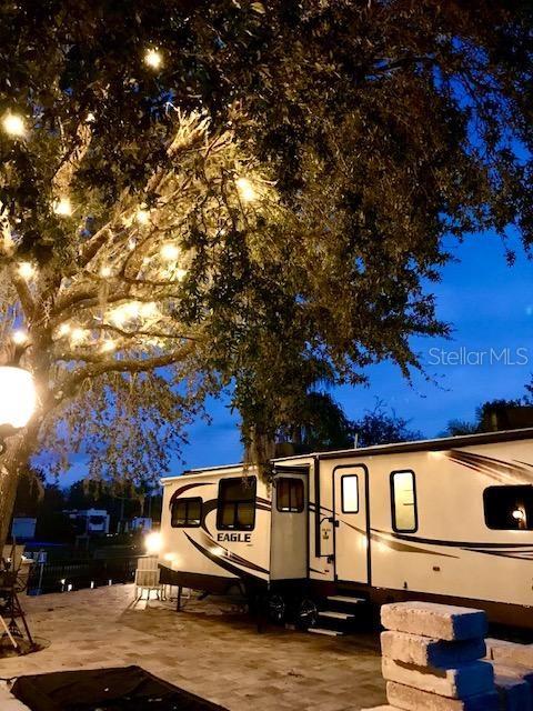 An Eagle travel trailer is parked on a paved patio beneath a large, illuminated tree — 436 WATERWAY DRIVE, RIVER RANCH, FL