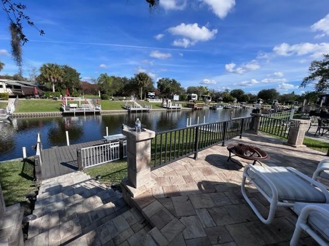 A paved patio with a fire pit overlooks a canal with private boat docks — 436 WATERWAY DRIVE, RIVER RANCH, FL
