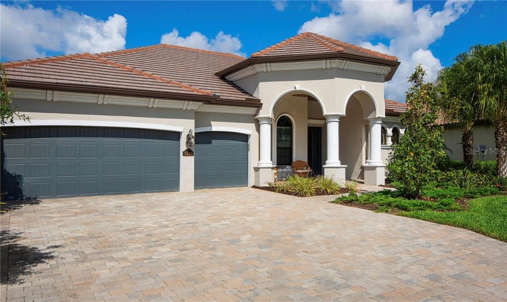 A single-story house with a paved driveway, a three-car garage, and a covered arched entryway — 5543 ARNIE LOOP, BRADENTON, FL