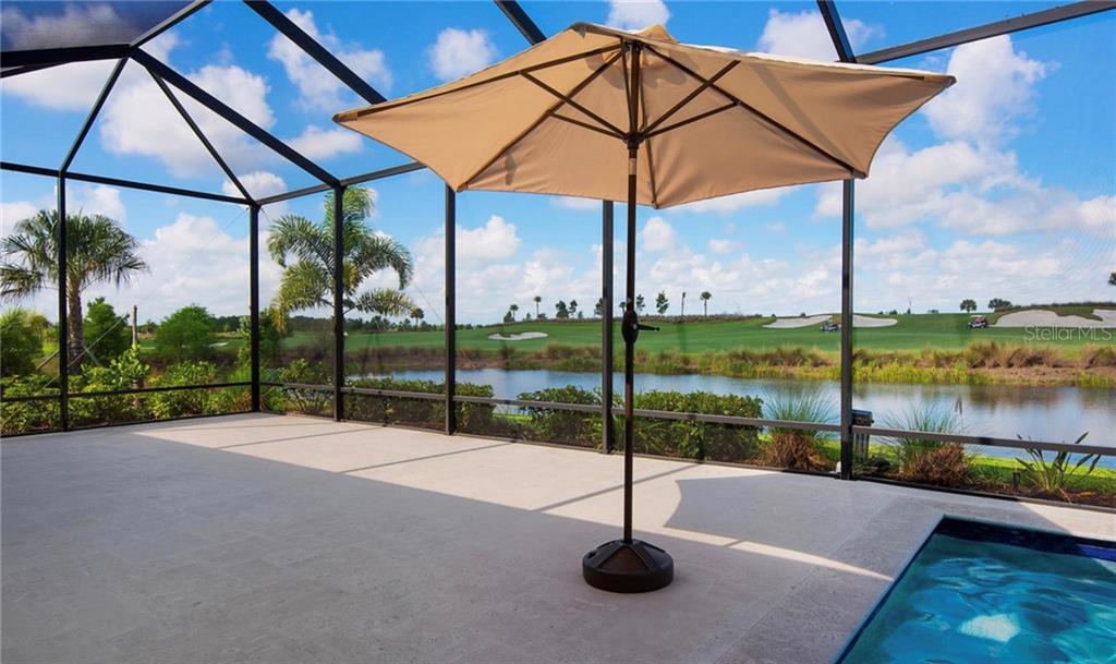 A screened-in patio features a pool, a patio umbrella, and a view of a golf course — 5543 ARNIE LOOP, BRADENTON, FL
