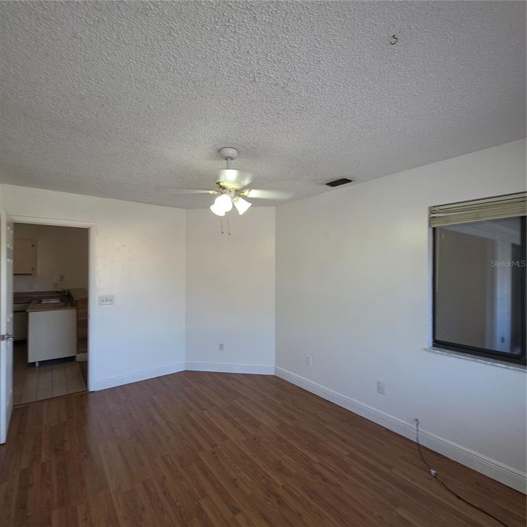 A kitchen features white cabinets, a white electric stove, and wood-look laminate countertops — 6031 SCOTCHWOOD GLEN UNIT 204, ORLANDO, FL