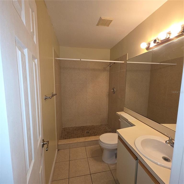 An empty room with wood-look flooring, white walls, a ceiling fan, and two doorways — 6031 SCOTCHWOOD GLEN UNIT 204, ORLANDO, FL