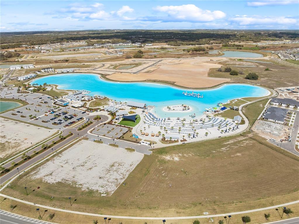 An aerial view shows a large man-made turquoise lagoon surrounded by a beach and parking — 31875 MAGNA GULF LOOP, SAN ANTONIO, FL