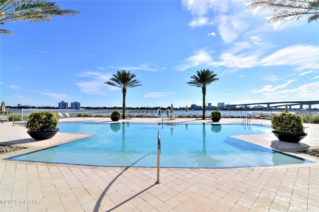 A swimming pool sits on a paved deck with palm trees overlooking a bay — 241 RIVERSIDE DRIVE UNIT 907, HOLLY HILL, FL