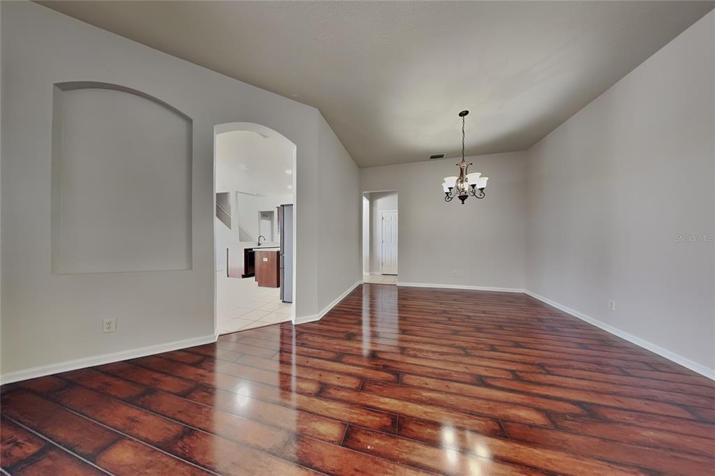 A dining room with dark wood-look flooring, a chandelier, and an arched entryway to the kitchen — 5714 99TH AVENUE CIRCLE E, PARRISH, FL