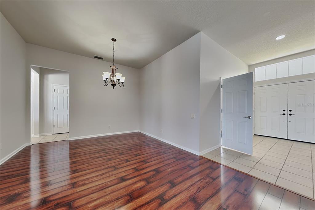 A dining room with dark wood flooring, a chandelier, and an adjacent tiled entryway — 5714 99TH AVENUE CIRCLE E, PARRISH, FL