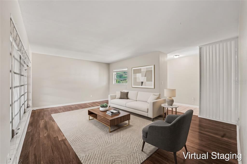 A living room with wood-look flooring, white walls, and a large window overlooking a porch — 521 W PALMEDEN DRIVE, LAKELAND, FL