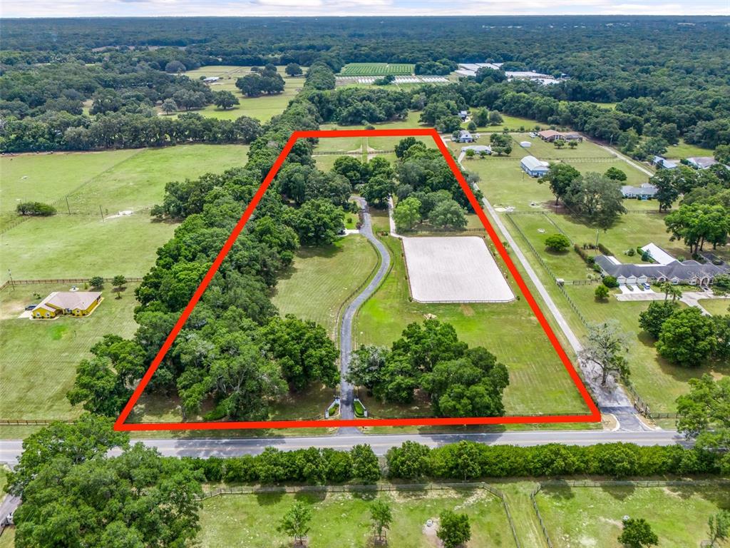 An aerial view shows a large, fenced rural property with a driveway and riding arena — 6975 NW HIGHWAY 225A, OCALA, FL