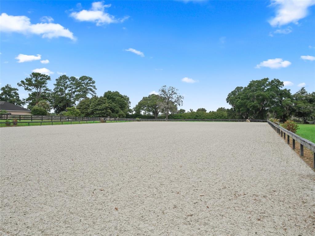 A large, fenced outdoor equestrian riding arena with a sandy surface under a blue sky — 6975 NW HIGHWAY 225A, OCALA, FL