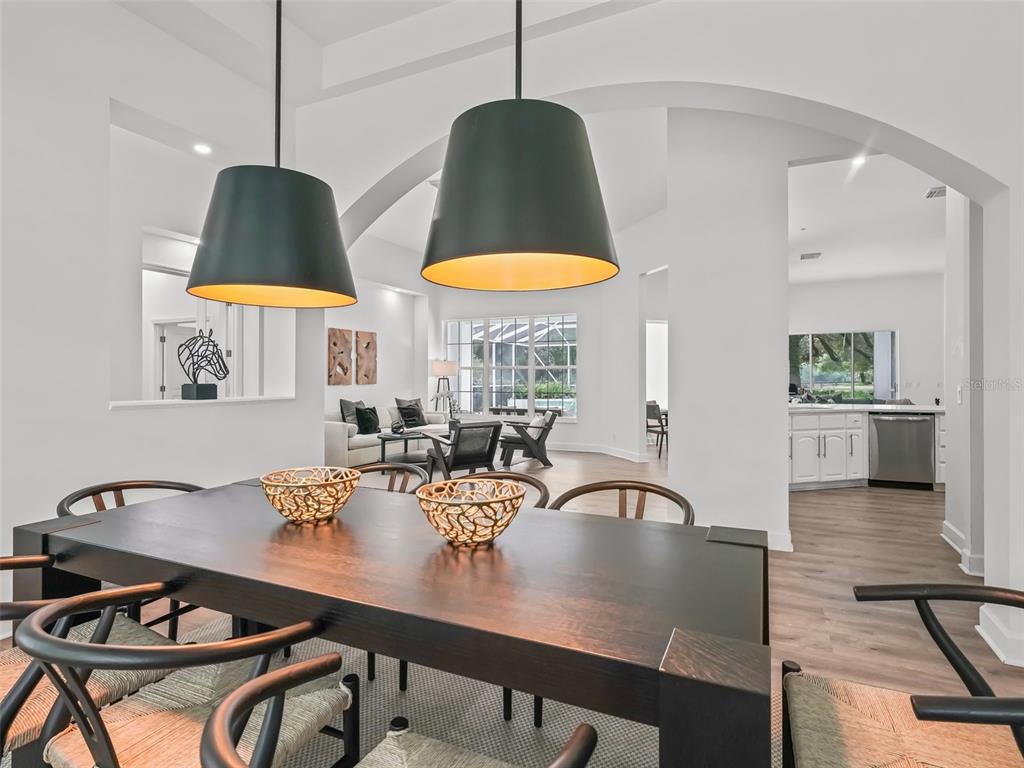 A dining area with a dark wood table and pendant lights overlooks a living room — 6975 NW HIGHWAY 225A, OCALA, FL